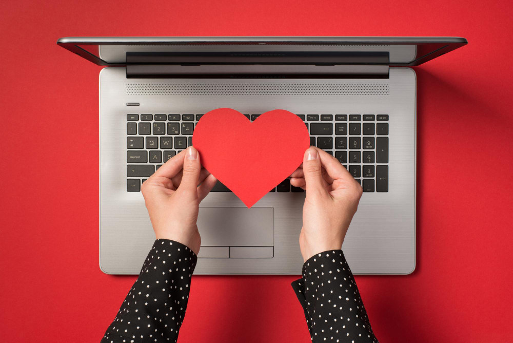 photo-grey-laptop-hands-holding-red-paper-heart-isolated-red-backdrop